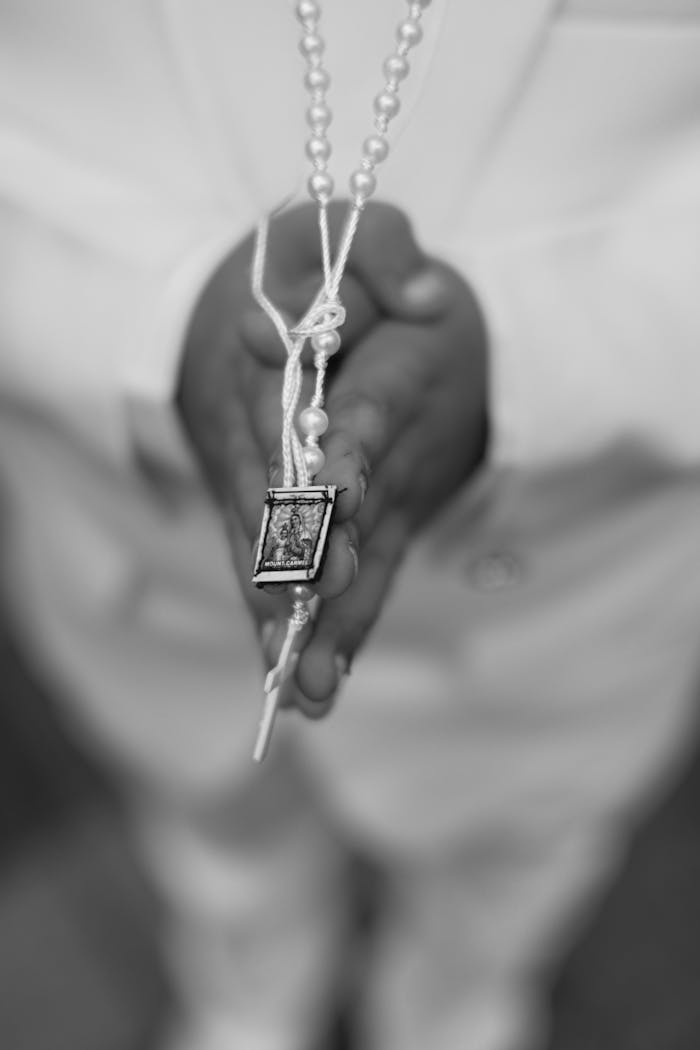 Black and white image showing hands holding a rosary in prayer, capturing the essence of spirituality.