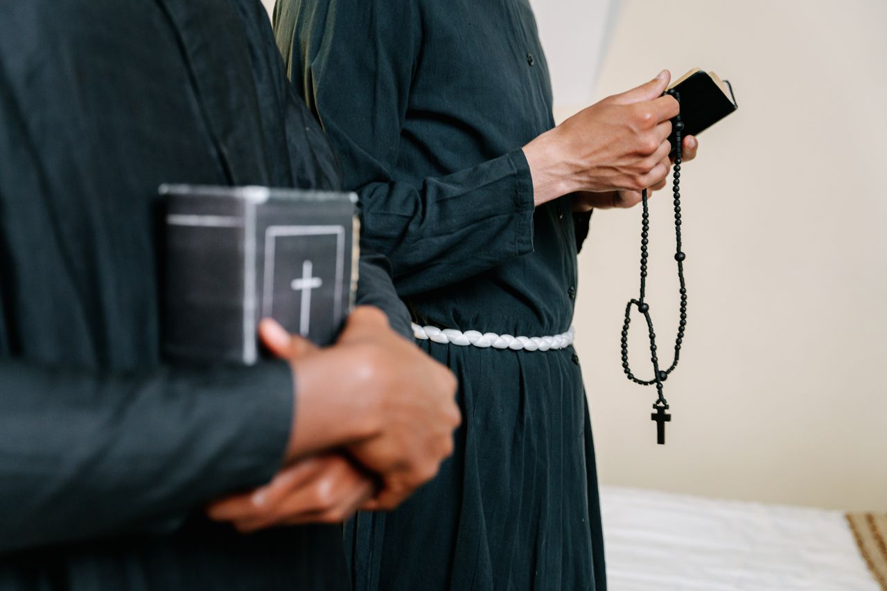 Clergy members in religious robes holding bibles and rosary beads, symbolizing faith.